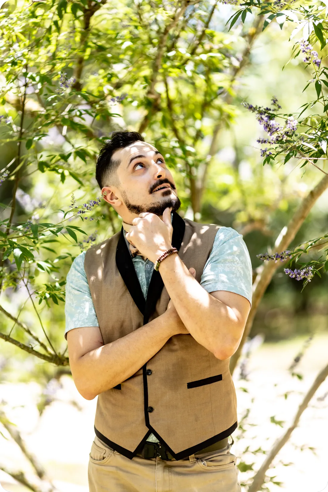 Geof Krum outdoors among green trees, looking up